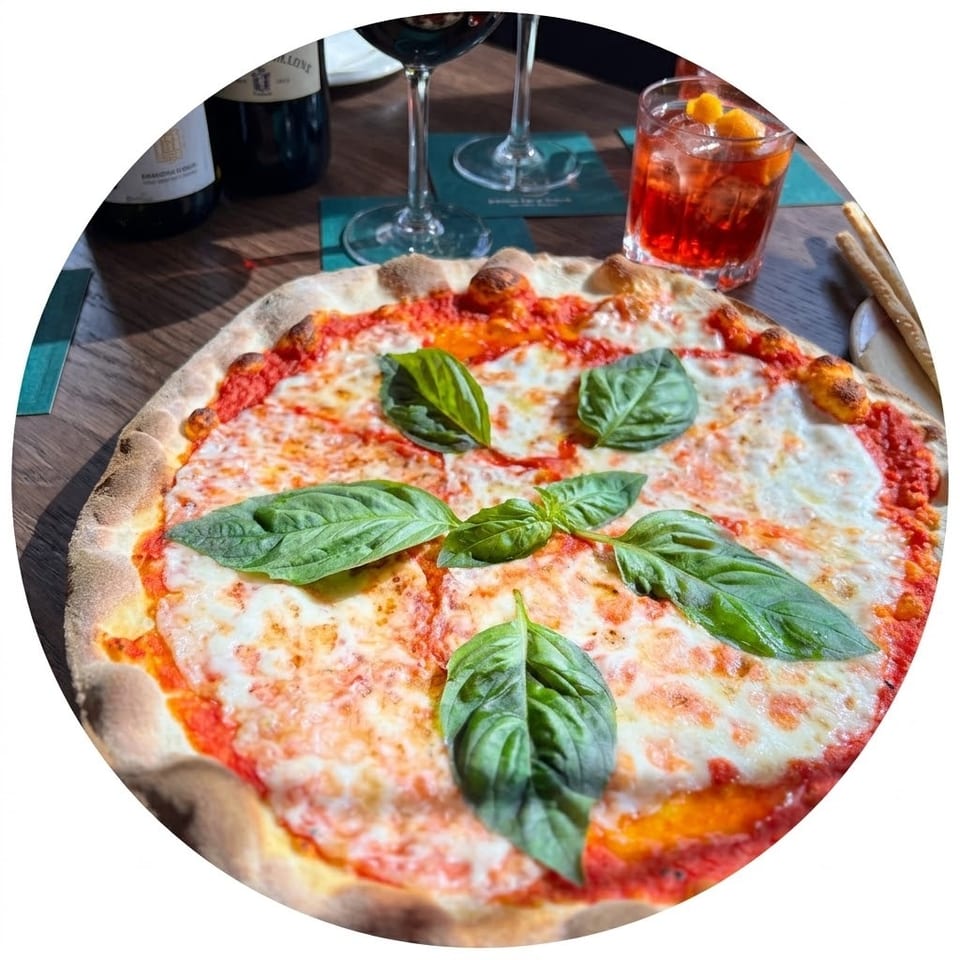Margherita pizza topped with melted mozzarella, tomato sauce, and fresh basil, accompanied by wine and an orange cocktail.